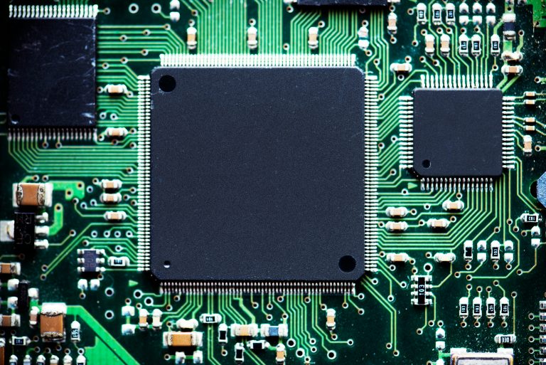 Detailed real photograph of a circuitboard with large black chips connecting green circuit lines to each other.